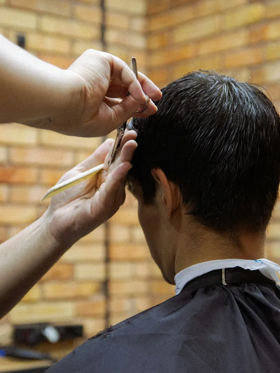A hairdresser cutting a man's hair with scissors
